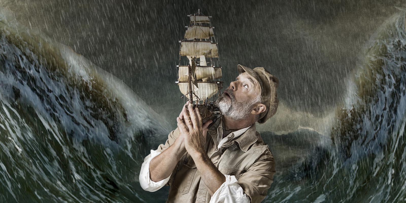 Johan Karlberg håller upp ett litet modellskepp. Omgiven av stormande hav.